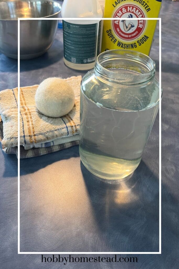Homemade laundry detergent with clean towels and a dryer ball