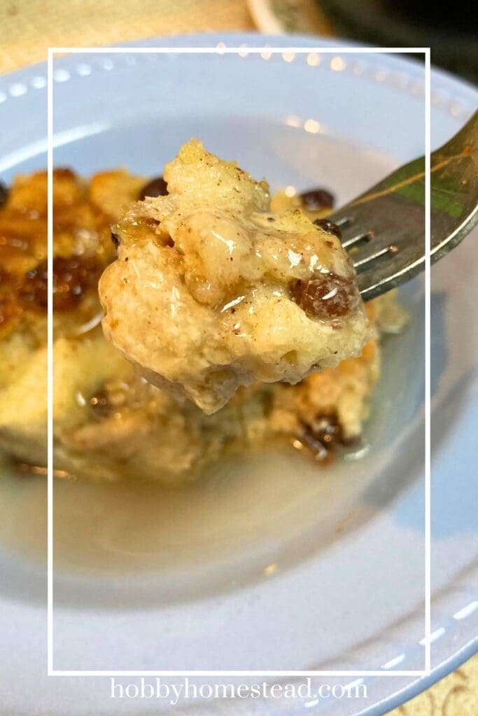 Fork full of bread pudding with vanilla sauce