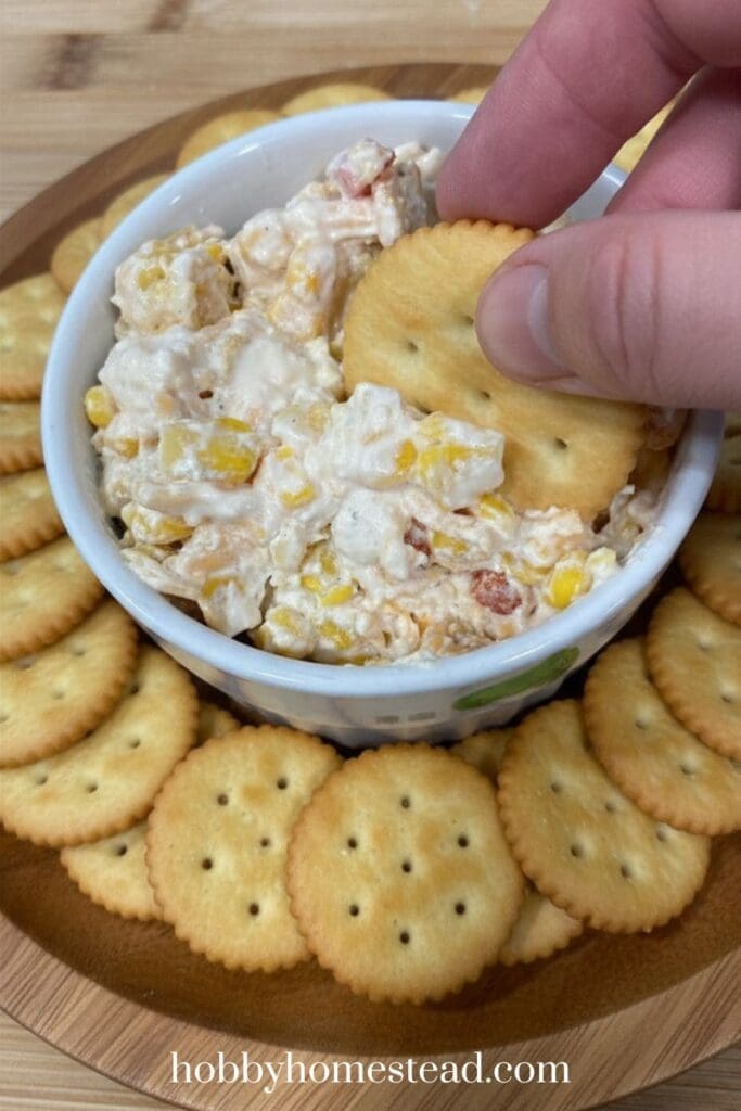 dipping into the corn dip with a cracker